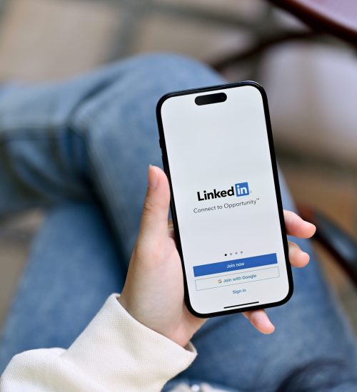 Chiang mai, Thailand - Feb 13 2023: close-up image of a woman's hands holding a smartphone with LinkedIn logo on screen, sign in or register on LinkedIn platform, iPhone with LinkedIn logo on screen.
